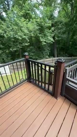 Custom deck railing detail with black aluminum balusters, illuminated post caps, and a self-closing gate at the stair landing, by Universal Design LLC in Bucks County PA.