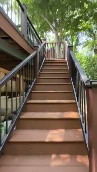 Wide custom deck staircase with matching composite treads and aluminum railing leading down to the yard, by Universal Design LLC in Bucks County PA.